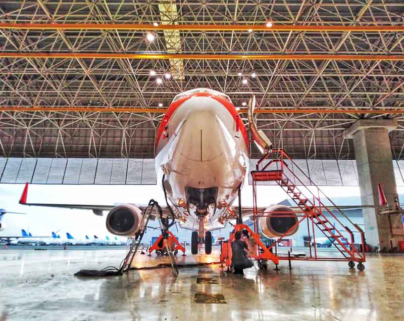 Aircraft is lifted by Dedienne Aerospace tripod jacks in a maintenance hangar